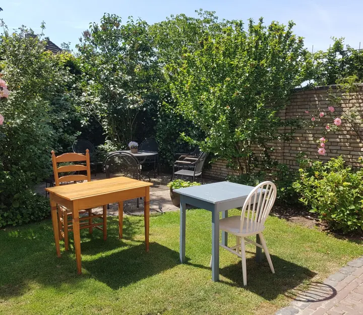 Tafeltjes en stoelen in de tuin achter het atelier