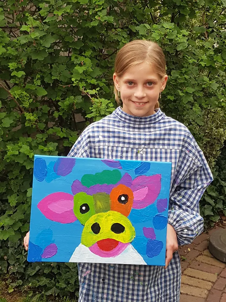 Een meisje laat trots haar schilderij van een koe zien